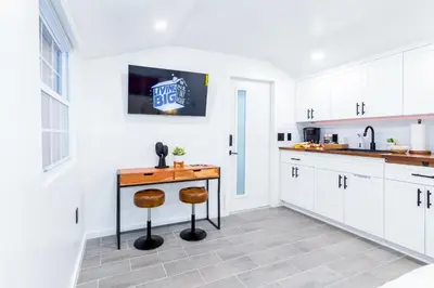 a kitchen with white cabinets and a wooden table at Smart Tiny House Garden in Miami Gardens