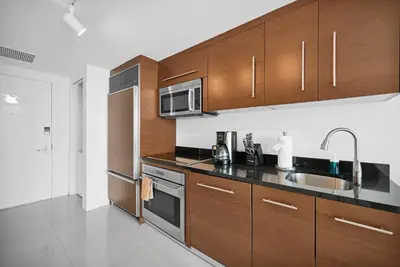 a kitchen with wooden cabinets and a sink and a microwave at Stylish Studio Icon, W Hotel Waterfront Building in Miami