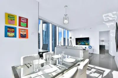 a dining room with a glass table and white chairs at Amazing 2 Bedroom at Icon in the Heart of Brickell in Miami