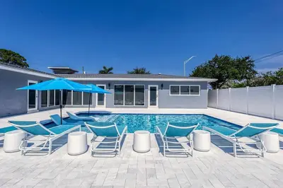 a swimming pool with chairs and a blue umbrella at Sunshine Manor 2017-1 in Fort Lauderdale