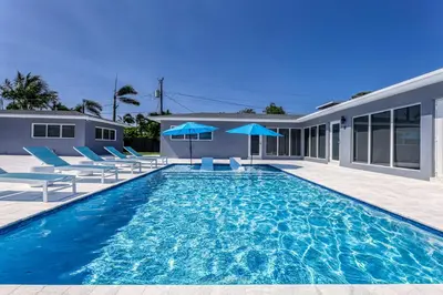 a swimming pool with blue chairs and a house at Sunshine Manors 2013 B in Fort Lauderdale
