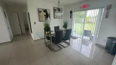a dining room with a glass table and chairs at BOOK ME, 3mins Hard Rock Stadium in Miami Gardens