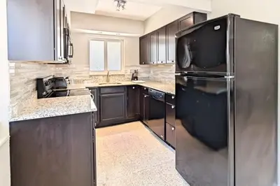a kitchen with black cabinets and a black refrigerator at Wiltonplex Complex in Fort Lauderdale