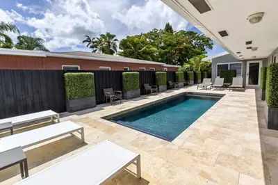 a swimming pool in a yard with chairs and a fence at Wiltonplex Complex in Fort Lauderdale
