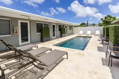 a swimming pool with chaises and chairs next to a house at Wiltonplex Complex in Fort Lauderdale