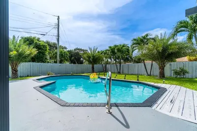 a swimming pool in a yard with a fence at Stunning Hollywood Pool Home in Hollywood
