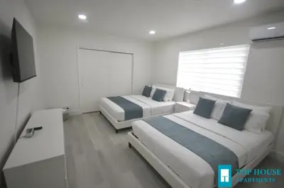 two beds in a white room with a tv at 251 Airport/Top House Apartments in Miami