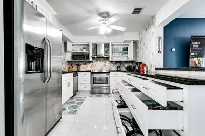 a kitchen with white cabinets and a stainless steel refrigerator at 5BD House - Pool+BBQ+King beds - 3 min to beach in Hollywood