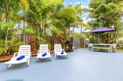 a patio with four chairs and a table and an umbrella at 5BD House - Pool+BBQ+King beds - 3 min to beach in Hollywood