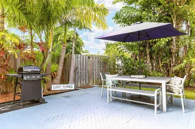 a patio with a grill and a table with an umbrella at 5BD House - Pool+BBQ+King beds - 3 min to beach in Hollywood