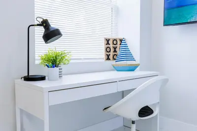 a white desk with a lamp and a plant at Serenity Lodge Condo in Miami