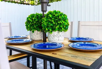 a wooden table with blue plates and green plants at Serenity Lodge Condo in Miami