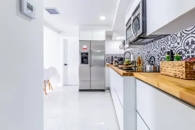 a white kitchen with a stainless steel refrigerator at Serenity Lodge Condo in Miami