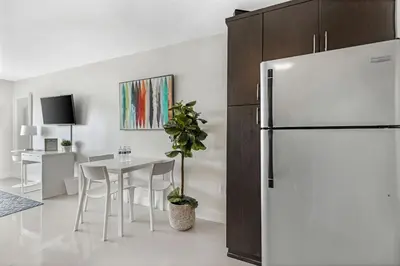 a white kitchen with a table and a refrigerator at Waterfront Studio Condo in the Heart of Miami - Skyline & Bay Views in Miami Beach
