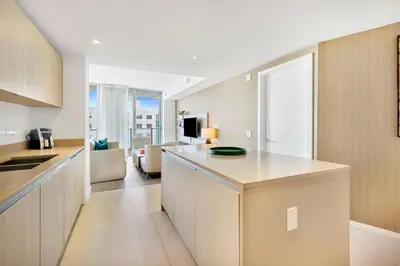 an apartment kitchen with a counter and a living room at Ocean View Balcony with Pool Gym Access in Hallandale Beach