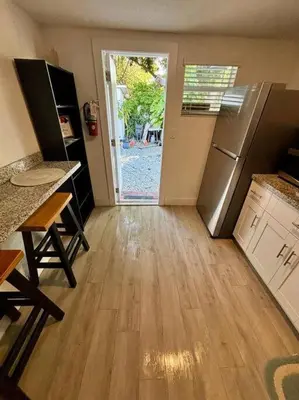 a kitchen with a refrigerator and a wooden floor at Quiet & Centrally located House - PRIVATE PARKING, LAUNDRY AND STORAGE FOR LUGGAGE in Miami