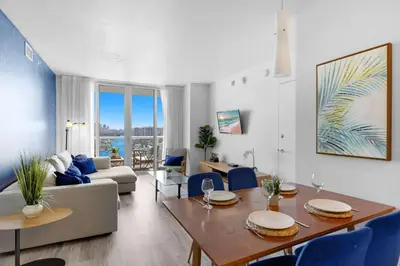 a living room with a table and blue chairs at Near Beach - Pool - Infinity View - Balcony - Gym in Hallandale Beach