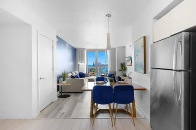 a kitchen and living room with a table and blue chairs at Near Beach - Pool - Infinity View - Balcony - Gym in Hallandale Beach