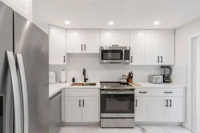 a kitchen with white cabinets and a stainless steel refrigerator at Villa at St James Unit A Luxury Pool Villa, Pet Friendly in Miami