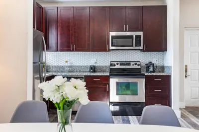 a kitchen with wooden cabinets and a vase of white flowers at Lauderdale Bliss - Mins to Las Olas & Beach in Fort Lauderdale