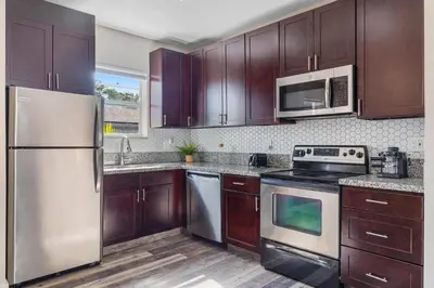 a kitchen with wooden cabinets and stainless steel appliances at Lauderdale Bliss - Mins to Las Olas & Beach in Fort Lauderdale