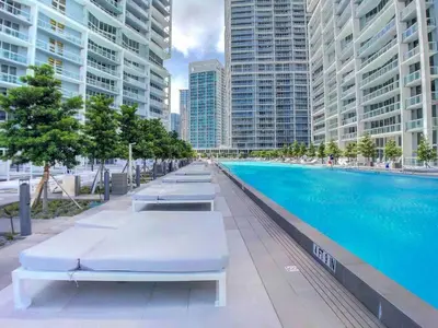 a swimming pool with chaise lounges next to tall buildings at ICON W BRICKELL BY IMD MIAMI Elegant River View 1BR 1BA in Miami