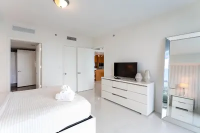 a white bedroom with a bed and a tv at ICON W BRICKELL BY IMD MIAMI Elegant River View 1BR 1BA in Miami