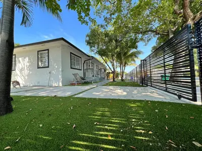 a house with a fence next to a yard at Stylish 2/1 centrally located! in Miami