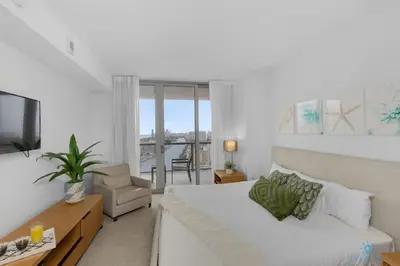 a white room with a bed and a tv and a couch at Amazing view - Balcony - Gym - Pool in Hallandale Beach