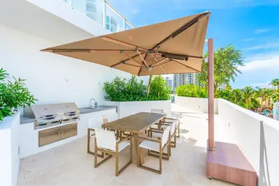 a patio with a table and a grill and an umbrella at Tiffany Emerald - Rooftop Pool, Gym, & Walk to Beach in Fort Lauderdale