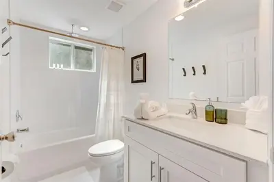 a white bathroom with a toilet and a sink at Wynwood Jumbo - Sleeps 16 & free parking in Miami