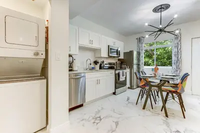 a kitchen with white cabinets and a table with chairs at Wynwood Jumbo - Sleeps 16 & free parking in Miami