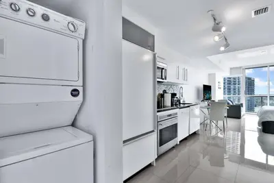 a white kitchen with white appliances and a dining room at Studio at Icon Brickell Luxury Waterfront Building in Miami