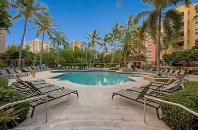 a pool with chairs and palm trees in a resort at Charming 2 bedroom 2 bathrooms at aventura in Miami