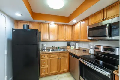 a kitchen with wooden cabinets and a black refrigerator at Fort Lauderdale Beach Resort by Vacatia in Fort Lauderdale