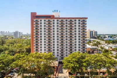 a tall building with trees in front of a city at Fort Lauderdale Beach Resort by Vacatia in Fort Lauderdale