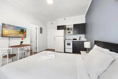 a bedroom with a white bed and a kitchen at Lovely condo in Miami Beach in Miami Beach