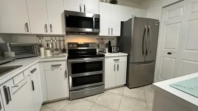 a kitchen with white cabinets and stainless steel appliances at Deluxe Yacht Club Condo Near the Beach in Miami