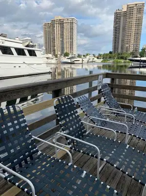 three blue chairs sitting on a dock with a boat at Pet-Friendly Aventura Pool, Beach, Golf, Gym in Aventura