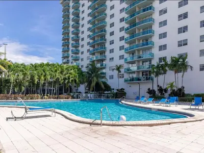 a swimming pool with chairs and a large building at Condominium Sunny Isles Ocean Reserve in Sunny Isles Beach