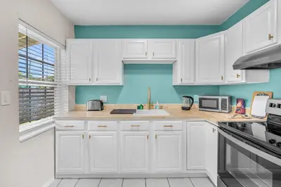 a white kitchen with blue walls and white cabinets at Bluewave Bungalow - #1 Charming & Comfortable 2 1 in Dania Beach