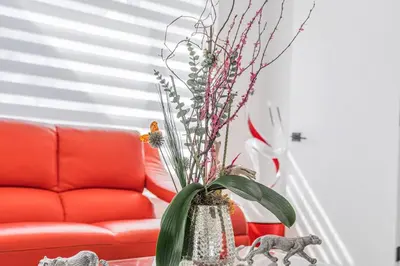 a vase with flowers in it next to a red couch at 3 2 Family friendly Brand New Home w Pool in Miami