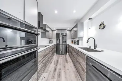 a large kitchen with wooden floors and stainless steel appliances at 3 2 Family friendly Brand New Home w Pool in Miami