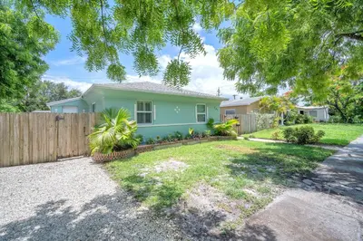 a green house with a fence in a yard at Bluewave Bungalow - #2 Charming & Relaxing 2 1 in Dania Beach