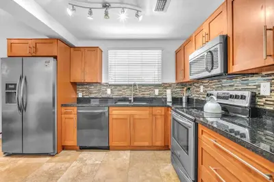 a kitchen with wooden cabinets and stainless steel appliances at Casa Santorini - Chic 4 2 near Grove & Brickell in Miami