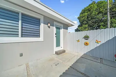 a white house with a fence and a door at Homey Studio near the Airport and Water Park in Miami