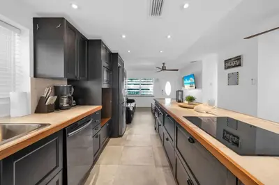 a kitchen with black cabinets and wooden counter tops at Renovated Gem: Prime Spotless Ideal in Miami