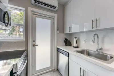 a kitchen with white cabinets and a sink and a door at Sunshine Manor 2013 in Fort Lauderdale