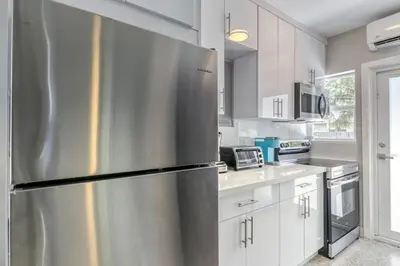 a stainless steel refrigerator in a kitchen with white cabinets at Sunshine Manor 2013 in Fort Lauderdale