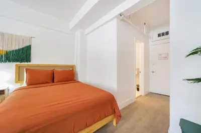 a bedroom with an orange bed in a white room at Tropics Hotel Miami Beach in Miami Beach